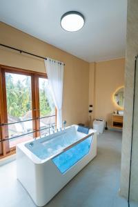 Una bañera grande en un baño con ventana. en Lemon Tree Hotel Bali, en Lovina 128 fotos más