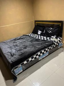 a bed with a black and white comforter on it at Stay Inn in Pattaya Central