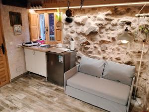 a kitchen with a couch and a stone wall at Casita con encanto tranquilidad VILLAVIEJA DEL LOZOYA Wi-Fi EN SIERRA DE MADRID Y A 50 MINUTOS DE CAPITAL in Villavieja del Lozoya