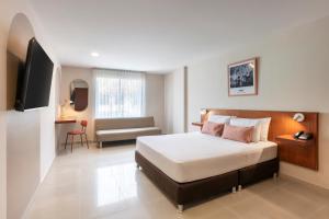 a bedroom with a bed and a couch and a television at Hotel MS Chipichape in Cali