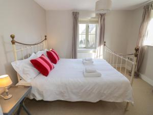 una camera da letto con un letto bianco con cuscini rossi di 2 Summers Way a Moreton in Marsh