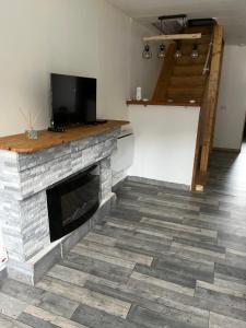 a living room with a stone fireplace with a flat screen tv at Maison de la nature in La Motte-dʼAveillans