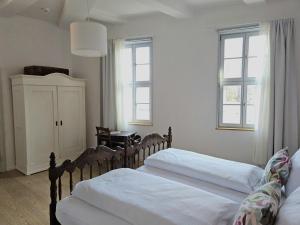 two beds in a bedroom with two windows at himmlischer Hof - Juwel von 1477 mit P, romantischer Innenhof, Kamin, Öko, Denkmal in Quedlinburg