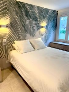a bedroom with a white bed with a palm leaf mural at Nid douillet à Cassis in Cassis +7 photos
