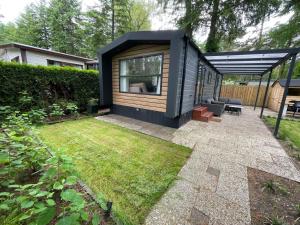 a small black tiny house in a garden at El Bohemia Veluwe rust, natuur & zwembad voor kids in Hoenderloo