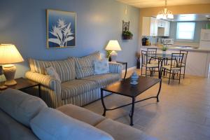 Una sala de estar con sofás y una mesa y una cocina. en Emerald Isle 105 by Alicia Hollis Rentals, en Fort Walton Beach
