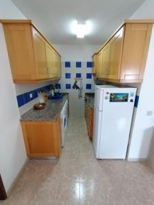 a kitchen with a white refrigerator and wooden cabinets at Casa Francis in Aljezur