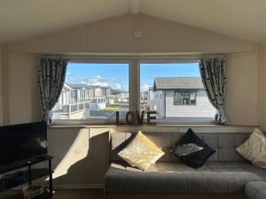 a living room with a couch and a large window at Cosy static caravan in rye! in Rye