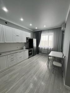 カラガンダにあるЖк Асыл Парк Юго востокのキッチン(白いキャビネット、テーブル、冷蔵庫付)