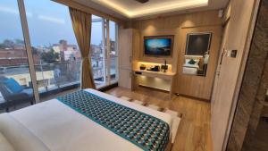 穆扎夫法尔普尔Hotel Central Tree的一间带床的卧室和一个带电视的阳台
