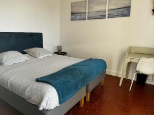 a bedroom with a bed with a blue blanket on it at UNE TERRASSE SUR LES TOITS in Aix-en-Provence +1 photo