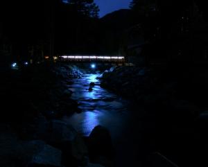 a night view of a river with a bridge in the background at The Inn on Fall River & Fall River Cabins in Estes Park