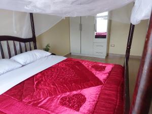 a bedroom with a bed with a red comforter at 2-Bed Apartment Sleeps 4 - Balcony - Pets Welcome in Namulanda