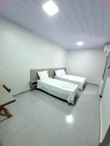 two beds in a room with white walls at Hotel Rota do Agro - Distrito Rosário in Posse +5 photos