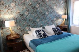 a bedroom with a bed with blue sheets and floral wallpaper at La Georginette in Saint-Georges-sur-Cher