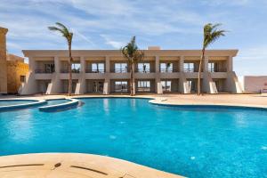 a large swimming pool in front of a building with palm trees at Miral Resort in Ain Sokhna
