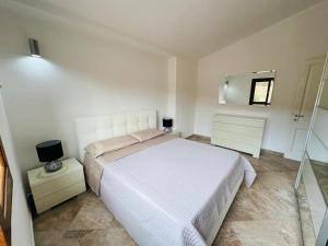 Un dormitorio con una cama blanca y un espejo. en Villa red bouganvillea, en Nuragheddu