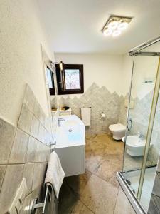 Un baño con lavabo, ducha e inodoro. en Villa red bouganvillea, en Nuragheddu 7 fotos más