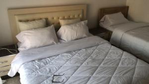 a bedroom with two beds with white sheets and pillows at Kris's Studio in Lezhë