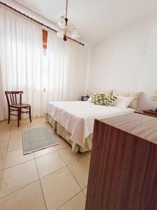 a white bedroom with a large bed and a chair at Casa Verdi Telti in Telti
