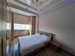 a bedroom with a white bed and a chandelier at Apartment in street Togolok Moldo 3 A in Bishkek