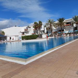 a large swimming pool with palm trees and buildings at Dia Brillante Costa del Silencio in Costa Del Silencio