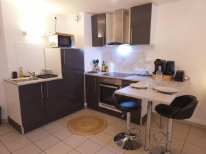 a kitchen with black cabinets and a table with bar stools at Montbel'appart - Charmant appart T1 tout équipé in Montbéliard +12 photos