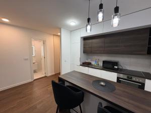 a kitchen with a wooden table and black chairs at I&I Tesla Apartments II in Kragujevac +2 photos