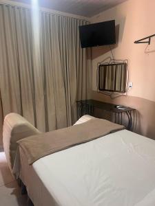 a bedroom with a bed and a television on the wall at Hotel Bee's Sorriso in Sorriso