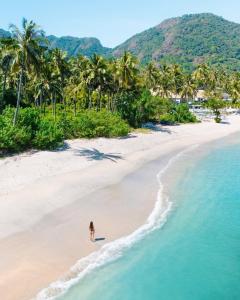 une personne se promenant sur une plage près de l'océan dans l'établissement Seven Secrets by Hanging Gardens, à Senggigi