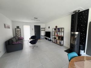 Grandchamp-des-FontainesにあるMaison 3 pièces - plain pied - 2 chambres lits Queen Size avec wifiのソファと暖炉のあるリビングルーム