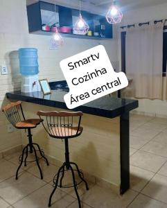 a counter in a kitchen with two bar stools at Flat de 2 quartos com AR na área central de GV com conzinha completa-garagem-wifi-Bom p grupos ou familias ou empresas in Governador Valadares