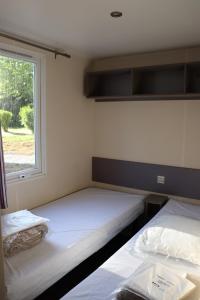 two beds in a small room with a window at Le Camping de Ripan in Bessenay