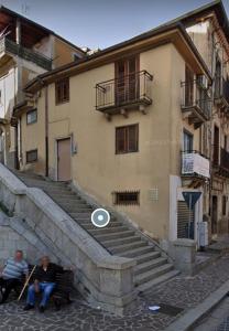 due persone sedute su una panchina di fronte a un edificio di Casa in Piazza a Cinquefrondi