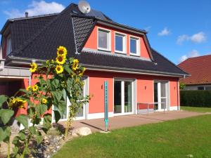 une maison rouge avec un toit noir dans l'établissement Haus Lütti, à Glowe