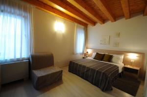 a bedroom with a bed and a chair and a window at Albergo Leon Bianco Gonars in Gonàrs