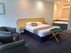 a bedroom with a bed and a chair and a tub at Village Motel in Havelock North