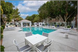 una piscina con sedie e tavolo e un tavolo bianco con sedie di Pure Suites Glendale Furnished Two Bed Pool Gym a Glendale