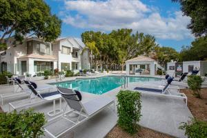una piscina con sedie e una casa di Pure Suites Glendale Furnished Two Bed Pool Gym a Glendale