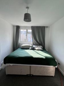 a bedroom with a bed with a green comforter and a window at The best house in Whitchurch