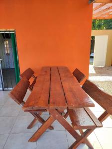 een houten tafel en twee houten stoelen naast een oranje muur bij Casa quinta La Ruchi in San Andrés de Giles