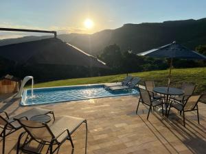 a patio with a table and chairs next to a pool at Vivenda Le Vin em Alfredo Wagner in Alfredo Wagner