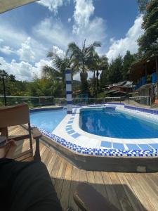 a large swimming pool with a person sitting on a chair next to it at Finca Hotel Santo Tomas El Oasis in Rionegro