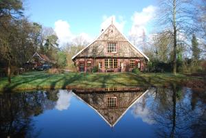 una casa vieja con su reflejo en el agua en B&B De Hagmolenbeek Boekelo, en Boekelo