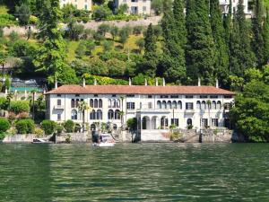 a large white house on the shore of a body of water at Trilly House in Perledo