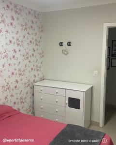 a bedroom with a bed and a dresser with pink flowers at Hospedagem em Meio a Natureza em Aperibé in Aperibé