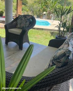 a patio with a wicker chair and a table with plants at Hospedagem em Meio a Natureza em Aperibé in Aperibé