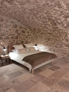 a bed in a room with a stone wall at Le Vieux Moulin de Jouques in Jouques +124 photos