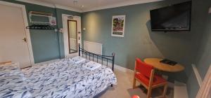 a bedroom with a bed and a table and a tv at The Portland Hotel in Folkestone
