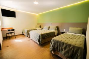 a hotel room with two beds and a table at Hotel Oly Plaza in Piracicaba